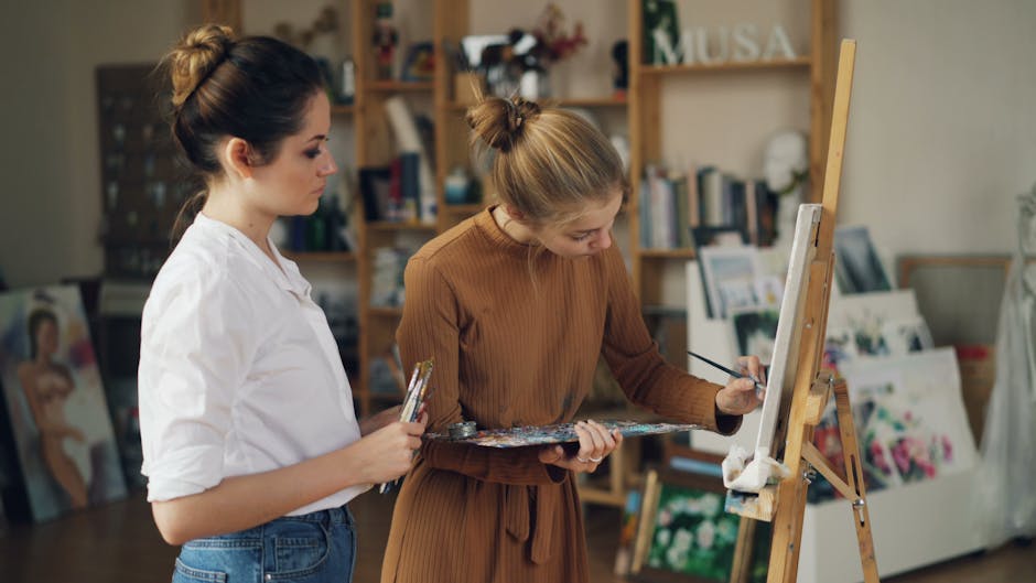 Two young women immersed in painting at an art studio with creative ambiance.