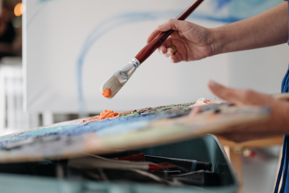 Artist's hand mixing vibrant colors on palette with brush in art studio.