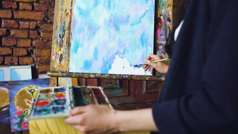 Close-up of an artist painting an abstract watercolor artwork on an easel.